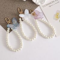 En gros, Porte-clés élégant papillon imitation perle, Chaîne de téléphone papillon en résine tendance, Bracelet de poignet à perles, Breloque de sac pour femmes