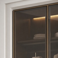 Système de dressing moderne de luxe avec portes en verre fumé, cadre foncé et éclairage intérieur LED chaud