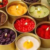 Bougie parfumée artisanale en cire de soja en forme de fruits, aux arômes de cerise, fraise et mûre, dans un pot en étain doré, idéale pour les fêtes.