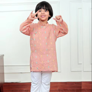 Lindo niño pequeño con kurta color melocotón con estampado colorido y pijama blanco, sonriendo en el interior con un atuendo festivo tradicional. - Product Image 1