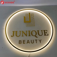 Enseigne personnalisée ronde givrée blanche rétroéclairée avec lettres en métal doré pour la décoration intérieure de salon de beauté