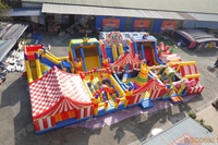 Parc d'attractions gonflable sur le thème du carnaval avec toboggans et jeux interactifs, aire de jeux commerciale pour événements en plein air