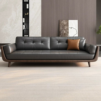 Canapé trois places en cuir pleine fleur gris foncé, dossier capitonné à boutons carrés, accoudoirs en bois découpé, style minimaliste du milieu du siècle