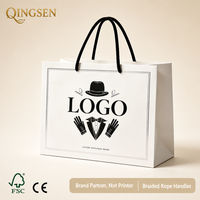 Sac shopping en papier blanc personnalisé OEM avec logo Fedora Tuxedo imprimé, poignées en corde tressée durables pour boutique de vêtements