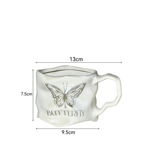 Taza de cerámica con diseño de mariposa, color blanco lechoso y plateado, con platillo para té, café y otras bebidas. - Product Image 2
