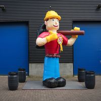 Belle poupée gonflable bricoleur joyeux a un casque de construction, un marteau, des outils pour la maison, l'entreprise ou l'emplacement de la fête