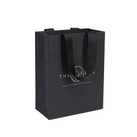 Sac en papier noir enduit de poignées de ruban intégrées avec logo en feuille d'or imprimé de luxe