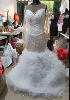 Robe de mariée sirène de luxe blanche perlée 2026 avec encolure illusion transparente, manches longues et traîne volumineuse à volants