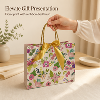 Sac cadeau en papier imprimé floral avec nœud en satin doré et poignées en corde torsadée pour l'emballage de cadeaux de détail