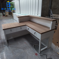 Comptoir de réception en forme de L avec dessus en bois grainé et cadre blanc, avec tiroirs, pour magasin d'optique, comptoir de caisse