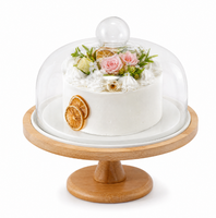 Support à gâteau rond blanc surélevé avec bordure conique en bois, dôme en verre transparent et bouton sphérique pour présentation sur table à manger