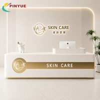 Comptoir d'accueil de luxe blanc pour soins de la peau avec logo à bande dorée et éclairage LED, idéal pour salon de beauté, clinique, spa, salle d'exposition, personnalisable