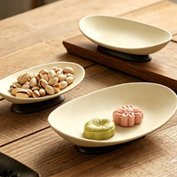 Plat en grès de forme bateau à rebord surélevé, sur support en bois d'acacia tourné, corps moucheté de sable, disponible en petites, moyennes et grandes tailles, idéal comme plateau de service pour canapé, sushi, ou plateau de présentation pour bijoux et articles de toilette.