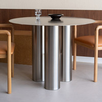Table à manger minimaliste de style italien en acier inoxydable, modèle inspiré des designers, luxe discret, pieds à trois colonnes, ambiance haut de gamme