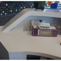 Bureau de réception incurvé personnalisé en Corian blanc avec base en acier inoxydable argenté pour hall d'hôtel