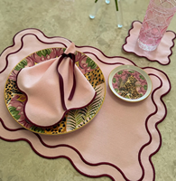 Set aus rosa Tischsets mit gewelltem Rand und burgunderroten Stoffservietten und Untersetzer, elegante Tischdekoration, kokettes Essensset