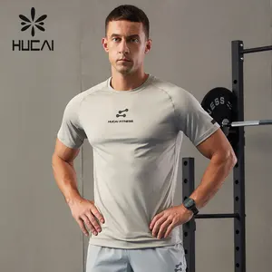 HUCAIカスタムポリエステルスパンデックスソフトカシオンドライフィットシリコンロゴ印刷フィットネスランニングジムTシャツ男性用