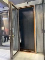 Una puerta abatible de madera maciza francesa moderna con un marco de aleación de aluminio y una puerta de vidrio exterior, delineando un ambiente cálido en el hogar