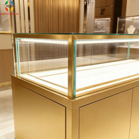 Vitrine à bijoux en verre trempé avec cadre doré brossé et éclairage LED pour magasin de détail haut de gamme, centre commercial de luxe, design écologique