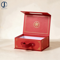 Boîte rigide rouge cerise mate écologique avec poignée à rivets dorés, design pliable, doublure en papier blanc, impression quadricolore UV haut de gamme