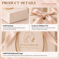 Sac cadeau de luxe personnalisé avec logo en feuille d'or gaufrée, en carton ivoire avec nœud en ruban de satin pour cliniques cosmétiques et salons de beauté