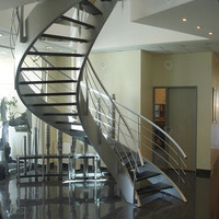 Design d'escalier courbé grandiose avec structure en acier carbone massif et garde-corps en verre transparent pour villa haut de gamme