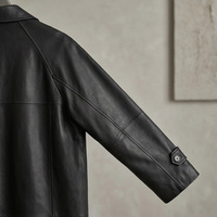Manteau long trench-coat noir mat en cuir de vache véritable pour femme, à revers crantés, simple boutonnage, poignets ajustables, fente arrière, coupe ample