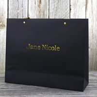 Sac en papier de luxe noir mat avec logo personnalisé, estampage à chaud doré, œillets métalliques et poignée en ruban pour boutique de vêtements, bijoux et cadeaux