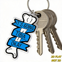 Porte-clés « It's Going Tibia Okay Bone » avec jeu de mots amusant sur l'anatomie et ruban bleu, breloque en acrylique découpée pour clés ou sac