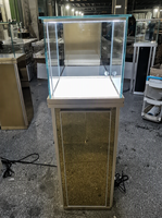 Présentoir sur pied en verre recyclable et écologique avec finition miroir personnalisée, éclairage LED et logo sur mesure pour bijouterie, horlogerie et showroom de marques.