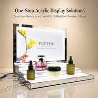 Présentoir à parfums moderne de luxe en acrylique à LED multi-niveaux, cadre en métal argenté, panneau arrière personnalisé à motif floral
