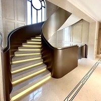 Rampe d'escalier moderne de luxe en acier courbé avec finition bronze antique et texture marbre en tons chauds pour villa intérieure