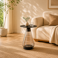 Table d'appoint ronde moderne et écologique avec plateau en acier inoxydable noir et base conique transparente fumée pour salon