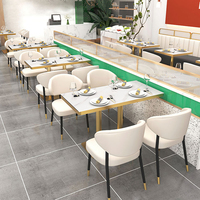 Banquette de restaurant avec cadre doré, cloison de séparation en verre intégrée, sièges modernes en cuir blanc, idéale pour centre commercial et hôtel