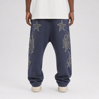Jogger homme Y2K personnalisé en usine, bleu marine légèrement délavé, avec patch étoile appliqué effet usé et coupe entrejambe basse, à revers.