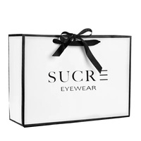 Sacs cadeaux blancs de luxe avec nœud, personnalisables avec logo de marque, élégants et à prix compétitif pour boutiques.
