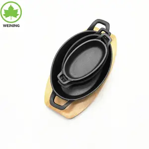 Forma oval da frigideira do ferro fundido, placa amassadora com bandeja de madeira