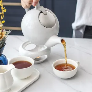 优雅的下午茶时尚白瓷茶壶，带浸泡器和蜡烛加热器