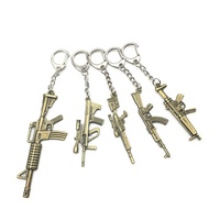 Vente en gros de porte-clés arme de feu croisé en acier inoxydable et en alliage de zinc pour hommes, bijoux artisanaux en métal, pendentifs, logo laser de style dessin animé