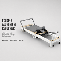 Reformer Pilates avec cadre en bois et coussinets gris pour l'entraînement et les étirements du tronc en studio