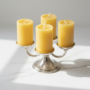 Natural beeswax pillar candles in varying heights, displayed on a wooden tray