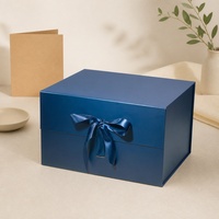 Boîte cadeau imperméable bleu foncé avec doublure en éponge, nœud en ruban sur le devant, structure pliable pour les marques de détail et les cadeaux saisonniers