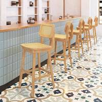 Banquette en bois de style Japandi avec dossier en rotin et chaises à coussin en cuir avec tables à piétement noir pour café