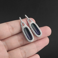 Ces boucles d'oreilles présentent un cadre ovale en résine serti de pierres en zircone cubique, alliant design moderne et éclat classique.
