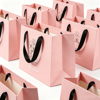 Sacs shopping en papier rose imprimés sur mesure de luxe OEM avec poignée en ruban pour les solutions d'emballage de marques de cosmétiques et de parfums