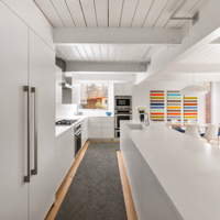 Meubles de cuisine modernes blancs à panneaux plats avec grand îlot, appareils électroménagers intégrés et design minimaliste en open space