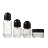 Ensemble de flacons cosmétiques et de pots à crème en verre transparent de luxe avec des bouchons en dôme noir et une pompe dorée pour l'emballage des soins de la peau