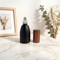 Vente en gros de flacons à bille en verre noir mat opaque de 12 ml, flacons de luxe pour huiles parfumées avec bille en acier et couvercle en bois foncé naturel