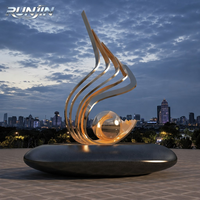 Sphère abstraite moderne en acier inoxydable plaqué or poli miroir, motif flamme en spirale ascendant, pour espace public extérieur, art métallique emblématique