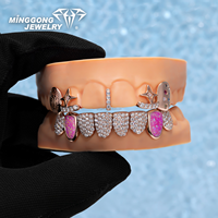Grillz ouverts personnalisés plaqués or rose et argent, avec détails empreinte digitale, accents de pierres précieuses colorées, pierres latérales en opale rose, et partie inférieure entièrement pavée de pierres.